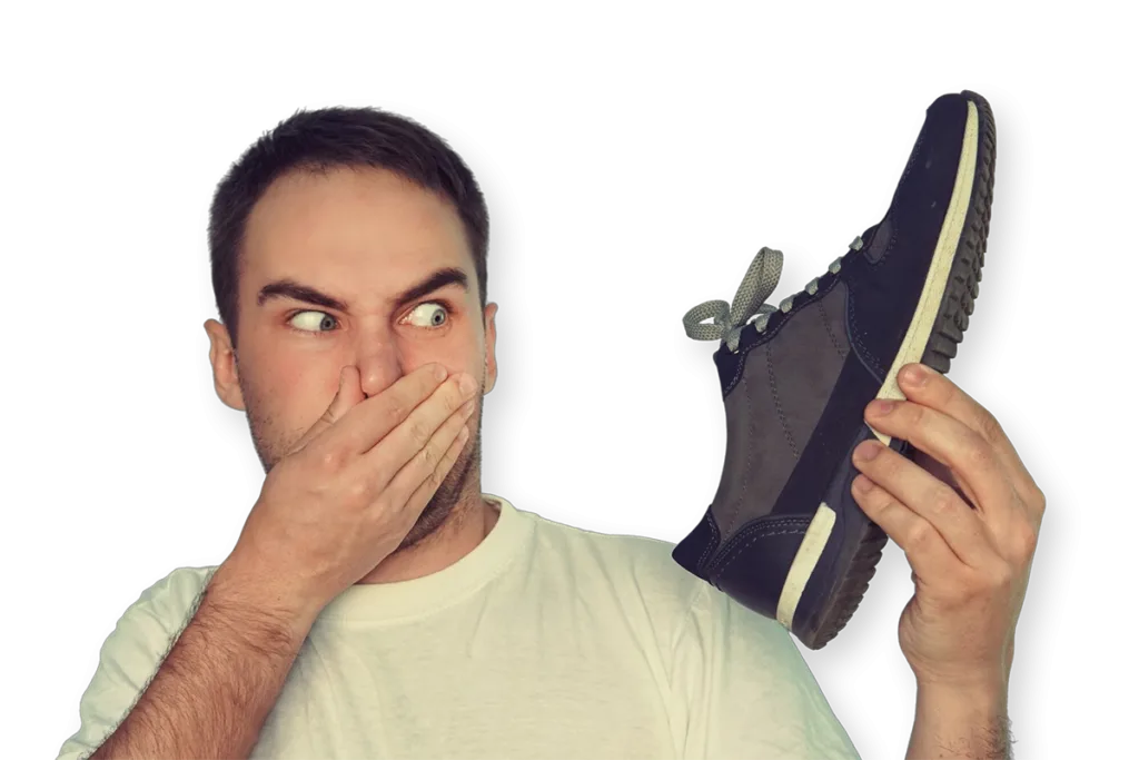 Man riecht an einem Sneaker, wenn man unter Fußgeruch und wiederkehrendem Fußgeruch leidet